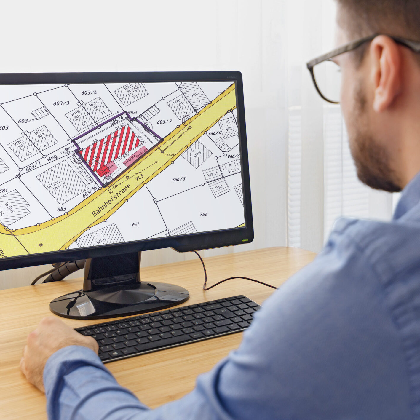 Mann am PC beim bearbeiten eines Lageplans